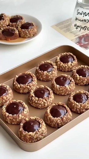 Chocolate Hazelnut Caramel Cookies 🥰 preparation take a bowl softened butter 125g powdered sugar 35g mix well one egg yolk mix well sift cocoa powder 18g milk powder 30g corn starch 30g cake flour 150g mix well cover the dough refrigerator for 1hour make the cookies take the dough each piece 20g make balls crushed hazelnuts baking pan baking paper mold size 4cm make holes Bake in a preheated oven 160C for 25min let it cool caramel preparation take a saucepan low heat water 20ml sugar 120g stir 