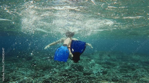POV following female free diver dancing underwater moving arms and blue flippers making bubbles. Happy girl fooling around in warm tropical ocean undersea. Enjoy vacation in Paradise island. Horsing.