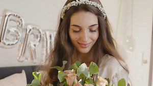 Bride holding bouquet with hair band with flowers, looking at camera while smiling | Free Stock Video Footage