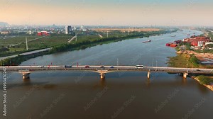 A barge navigates the Day River under a bridge in Ninh Binh, Vietnam. The river is a key waterway for transport of goods and materials.