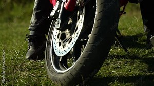 A guy on a motorcycle. Young handsome guy with his motorcycle in the mountains. Motorcycle wheel close-up. The guy sits on his motorcycle. Stock Video