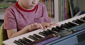 Child playing piano music keyboard. Close up of hands of 5 year old preschooler boy playing on electronic keyboard.
