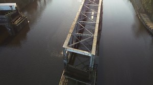 Victorian Era Aqueduct across Manchester Ship Canal, UK. Tracking move along steel structure to reveal road bridge and brick tower.