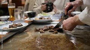 Japanese chef slicing wagyu Kobe beef steak juicy meat while grilling meat in a grill at a japanese restaurant prepared to served marble beef tepanyaki cooking Japanese style