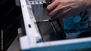 Extreme close-up of unrecognizable computer repair technician unscrews cover on motherboard with screwdriver to install new SSD disk. Stages of assembling professional electronic equipment for work.