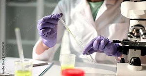 Laboratory worker takes urine sample with pipette pouring into glass tube. Woman in rubber glows does detailed urine test at table slow motion