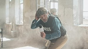 Military journalist interviewing brave defenders in smoky abandoned building. Soldiers speaking with microphone while loud explosion rang out. Correspondent commenting on events in live broadcast.
