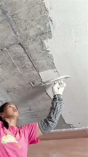 A woman who is flattening a cement dough on a building