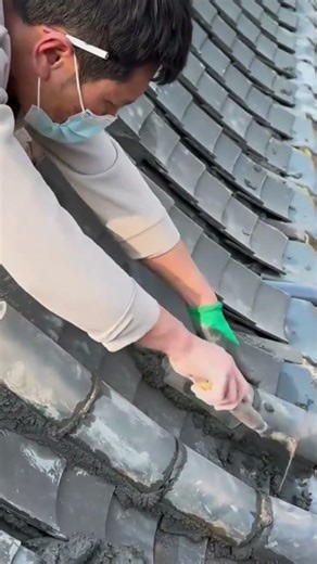 Installing traditional grey ridge roof tiles on an ancient building with wet cement