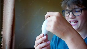 school age boy with glasses holds a light bulb.