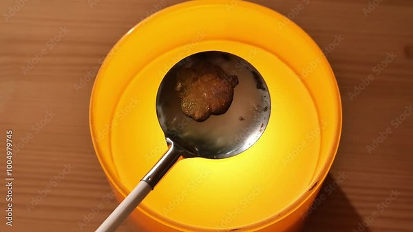 Fun tin casting.tin clover figurine in spoon over candle flame in an orange candlestick on a wooden table.Fortune telling with melting tin.Molten tin over a candle flame.Preparing for fortune telling