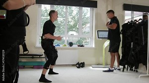 EMS training - fitness instructor works with athlete wearing ems suit - calibration