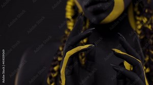 Face art. Woman with black and yellow body paint. Young african girl with colorful bodypaint. An amazing afro american model with yellow makeup.