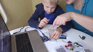 Programming for children. A teacher teaches a child at a robotics and IT school. Boy learning to code control board
