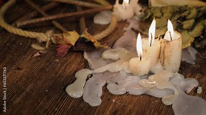 Preparation of items for witchcraft. Burning candles on the background of an open fire in the fireplace, dripping wax. Clay pots with components of poison. Concept of mysticism.