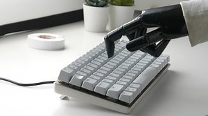 Fake hand typing on a computer keyboard. Handicap person working with a fake limb.