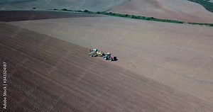 Aerial drone shot of a farmer sowing his fields with grain. Tractor and planter in a dry field. Overberg, South Africa sowing season.