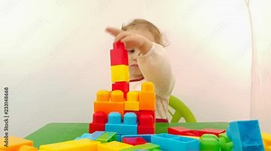 Little girl playing with construction building blocks when sitting at a small table. Children education concept