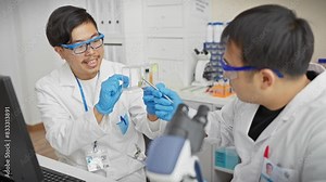 Two men analyze samples in a laboratory setting, wearing lab coats, gloves, and safety goggles.