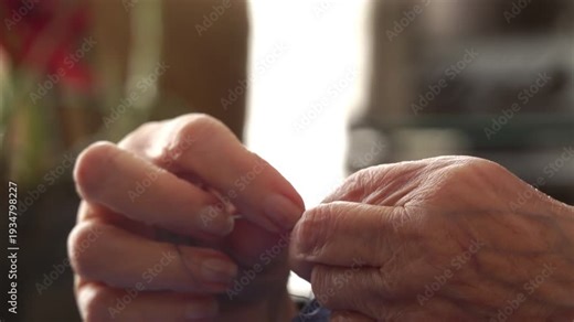 The hand of an elderly lady sewing. The woman seamstress is sewing something. Old woman's hands, close up.