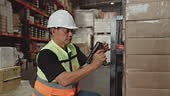 Mature warehouse workers utilize scanners to verify and scan the...