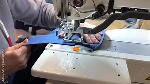 Textile industry. Loops and buttons. Industrial sewing equipment, a machine for loops. The girl makes loops on a blue shirt.