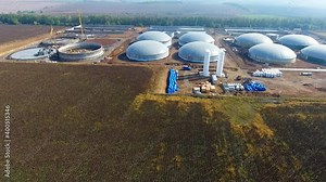 Construction of biogas plant on field. Large storage reservoirs for biogas production in environment. Industrial infrastructure among nature. Aerial view.