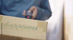 Delivery man scanning boxes a barcode packages with a handheld barcode scanner