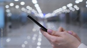 Smartphone in female hands, close up shot, young adult woman type message using instant messaging application. Blurred corridor on background, modern interior of international airport
