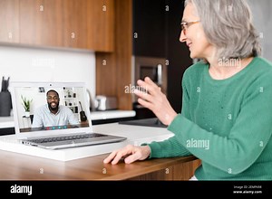 Senior online tutor, trainer, coworker is talking via video connection with an African man on the laptop screen. Mature woman is using computer app for video meeting with biracial colleague, employee Stock Photo - Alamy