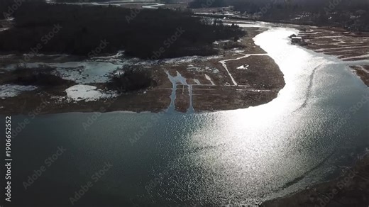 Drone aerial over Essex Bay and the Great Marsh, Massachusetts, showing winding tidal channels, salt marsh pools and barrier beach leading to the Atlantic Ocean, clear daylight.