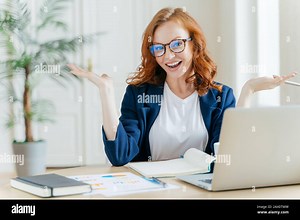Image of cheerful redhead businesswoman watches webinar or tutorial video, uses free internet connection, raises palms with hesitation, sits at deskto Stock Photo - Alamy