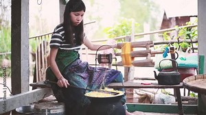 Woman weaving and spinning natural colorful threads or yarn. Raising thread for making thread. Boiling the cocoons of the silk worms. Silk production process in Thailand