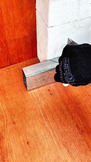 Gloved hand positions angled metal piece for duct joint fitting