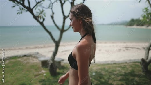 Tourist woman walking beach garden on tropical Thailand island. Young female in bikini relax and enjoy on summer holiday vacation. Side view, slow motion