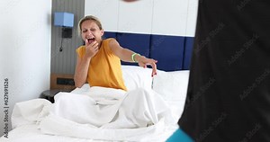 Woman sitting in bed and laughing at man standing in front of her 4k movie. Problems with male potency concept