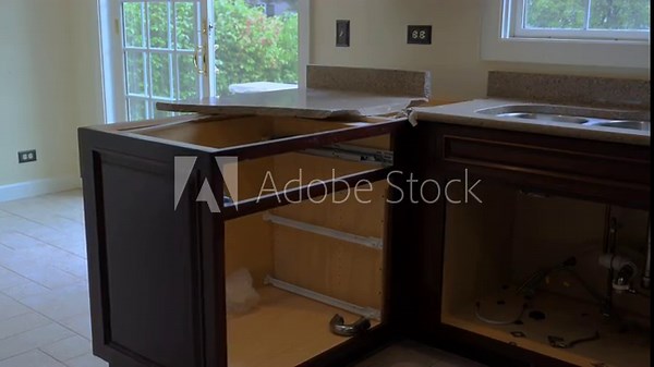 Removal of the old kitchen countertop during a home renovation project. The worker lifts and detaches the laminate counter, preparing for new installation.