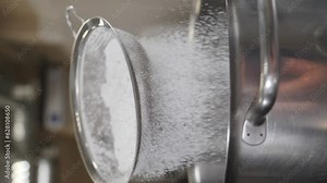 Bakery concept. Ingredients for sweet dessert making, Vertical footage. Smooth movement on slider. Metal bowl. Slow motion. Flour being sieved. Chef sifts powdered sugar through sieve to prepare dough