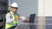 Engineer use digital laptop to examining solar panels on rooftop...