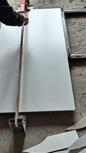 cutting a large ceramic tile with a manual cutter by scoring the surface and snapping it cleanly
