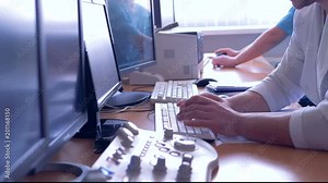 Two doctors are sitting in front of computers and typing