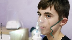 Child inhale using a nebulizer. 13-year-old boy in a nebulizer mask close up