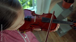 Little girl 5 years old in a red dress plays the violin. Slow motion.