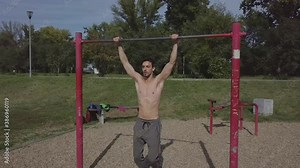 Beautiful muscular young Caucasian man doing pull ups in nature alone during individual practice. People and health concept.