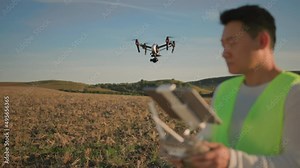 Young asian engineer with digital tablet flying black drone over field, monitoring harvest indicators and soil condition. Agriculture technologies. New world.