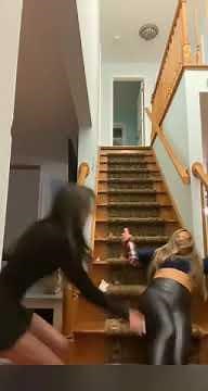 Girl falling down the stairs and breaking a fake champagne bottle.