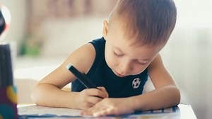 Drawing. Little boy with pencil coloring at home. Child draws at the table. Psychology of the child's personality. Help gaining confidence. Creativity and education concept.