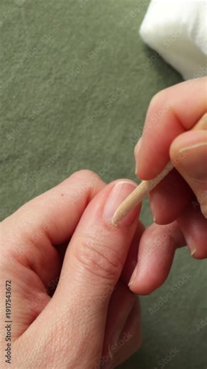 Pushing back cuticles with wooden orange stick. Close-up natural nail care routine, manicure at home
