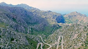 Cars, buses and motorcycles drive on European curved road in Majorca, Spain. Nus de Sa Corbata is a spectacular panoramic snake-like road with curves and rocky landscapes by the Mediterranean.