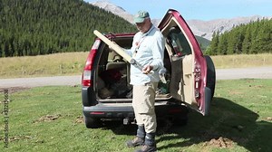 Hopeful, solitary Fly fisherman assembles a split cane fly rod prior to fishing for native Cutthroat Trout along the Powderface Trail in the Canadian Rockies Region of southwestern Alberta.